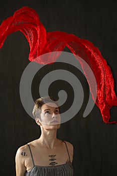 Young woman in silver dress with red scarf floating above.