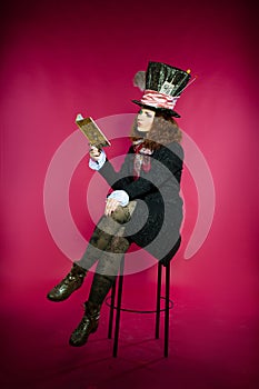 Young woman in the similitude of the Hatter reading book sitting