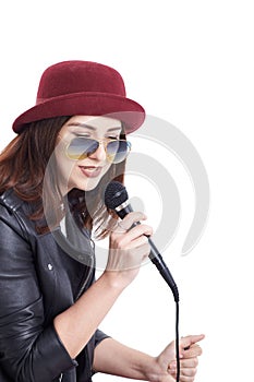 A young woman singing with a microphone wearing a white t-shirt