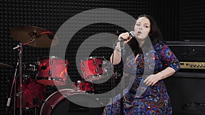 Young woman is singing and performing beautifully in sound recording studio, voice recording studio. Female singer performs lyric