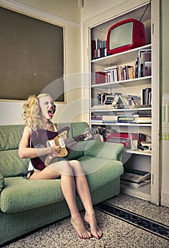 Young woman singing and playing the eletric guitar