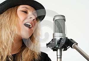 Young woman singing with studio microphone