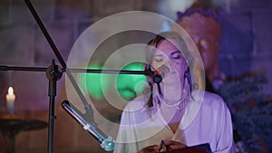 a young woman sings mantras in front of a microphone at her birthday party