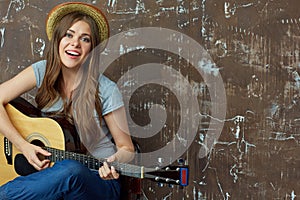 Young woman sings and plays on gitar.