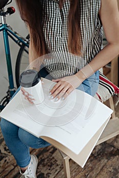 Young woman sipping coffee or tea and reading magazine