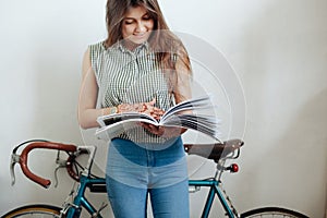 Young woman sipping coffee or tea and reading magazine