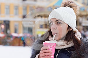 Young woman sipping a hot drink in winter weather