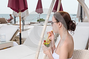 Young Woman Sipping Tropical Drink on Resort Patio