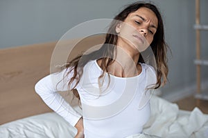 Young woman sit in bed suffer from backache