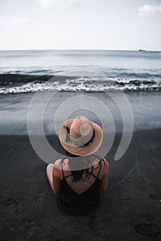 Young woman sit in the black sand beach