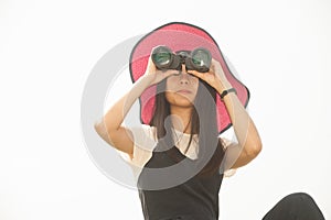 Young woman sit on ground seeking Binoculars .