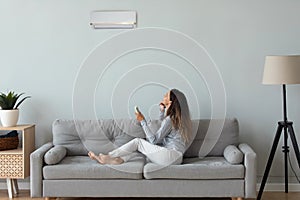 Young woman turn on air conditioner in living room photo