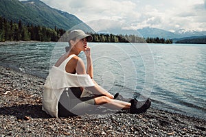Young woman sit and relax on the mountain lake wearing sport clothes in Alaska trip.