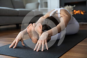 Young woman sit in Seated Forward Bend yoga asana