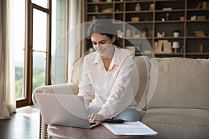 Young woman sit on sofa working or studying on laptop