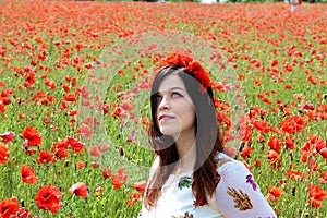 Young woman sitiing in poppies looking up