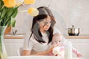 Young woman siting and feeding baby girl