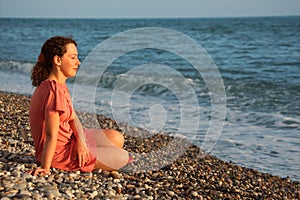 Young woman sits ashore of sea