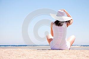 Young woman sits on the beach