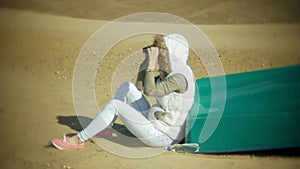 Young woman sits on the beach outside of the boat and looks through binoculars