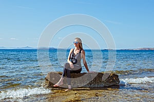 Young woman  sits on a boulder in the sea