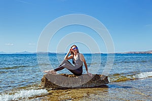 Young woman  sits on a boulder in the sea