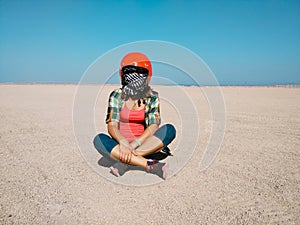 Young woman sits in the desert wearing a helmet for buggy.