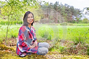 Young woman sits in forest near meadow