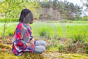 Young woman sits in forest near meadow