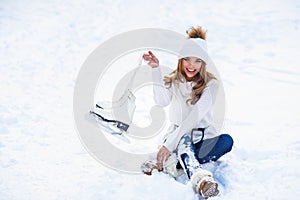 Young woman sits on the frosty snow in winter park. Winter holidays concept.