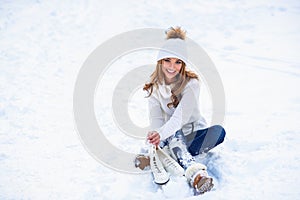 Young woman sits on the frosty snow in winter park. Winter holidays concept.