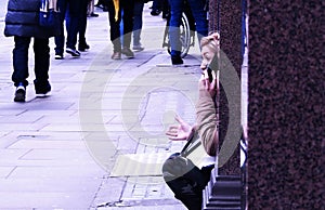 Street talk. A woman sits in an alcove of a shop window having a heated discussion on her Smart Phone. Shaftesbury Avenue London