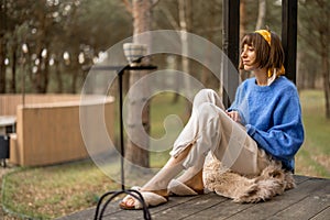 Woman rests near wooden cottage in nature