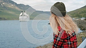 Young woman sits in port watch cruise ship leave