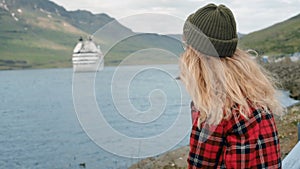 Young woman sits in port watch cruise ship leave