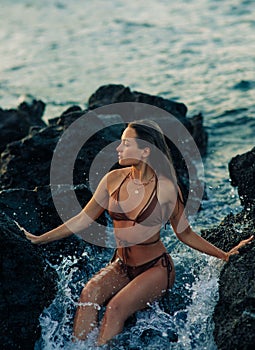 Young woman sits on rock near sea