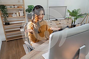 Young woman sits at table and looks at computer Video duets at home or with friends at home