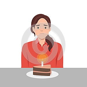 Young woman sits at table with piece cake with candle and suffers from absence of relatives and friends. Unhappy mother celebrates