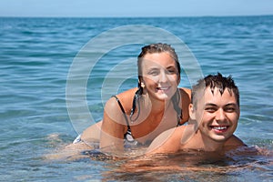 Young woman sitting astride man in sea near coast