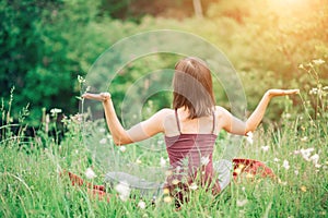 Young woman sitting back with her hands open in nature in the summer on a Sunny day. Health, yoga, harmony, relax