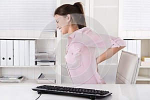 Young woman sitting with backache in the office.