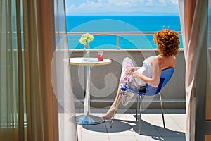 Young woman sitting on the balcony at the see