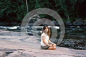Young Woman Sitting on Bank of Stream