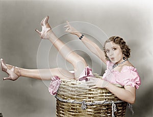 Young woman sitting in a basket looking surprised