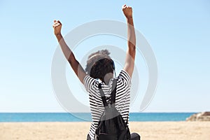 Young woman sitting by the beach and enjoining music on headphones