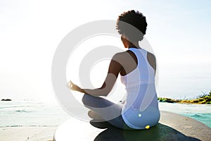 Young woman sitting at beach in yoga pose