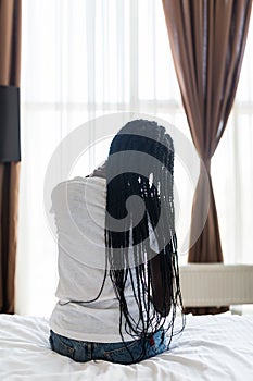 Young afro american woman sitting on the bed with pain in neck