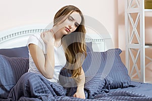 Young woman sitting on the bed with pain in neck in the morning, suffer girl - Uncomfortable mattress