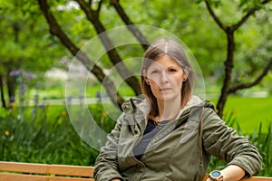 Young woman sitting on a bench in a city park. Conceptual photo. Portrait of a young woman