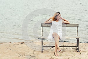 Young woman sitting on bench at lake and smiling.